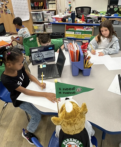 Second grade students making posters at their desks