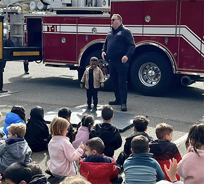 Students listening to a fire fighter in front of their fire truck