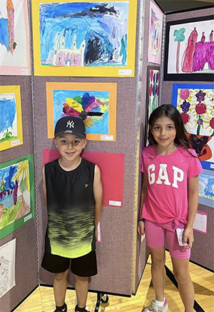 Little girl and boy in front of artworks on wall