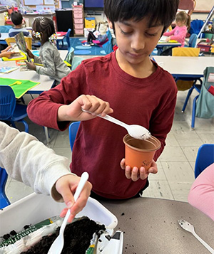 one student filling a pot with dirt