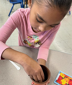 female student using her hands to put dirt in a pot